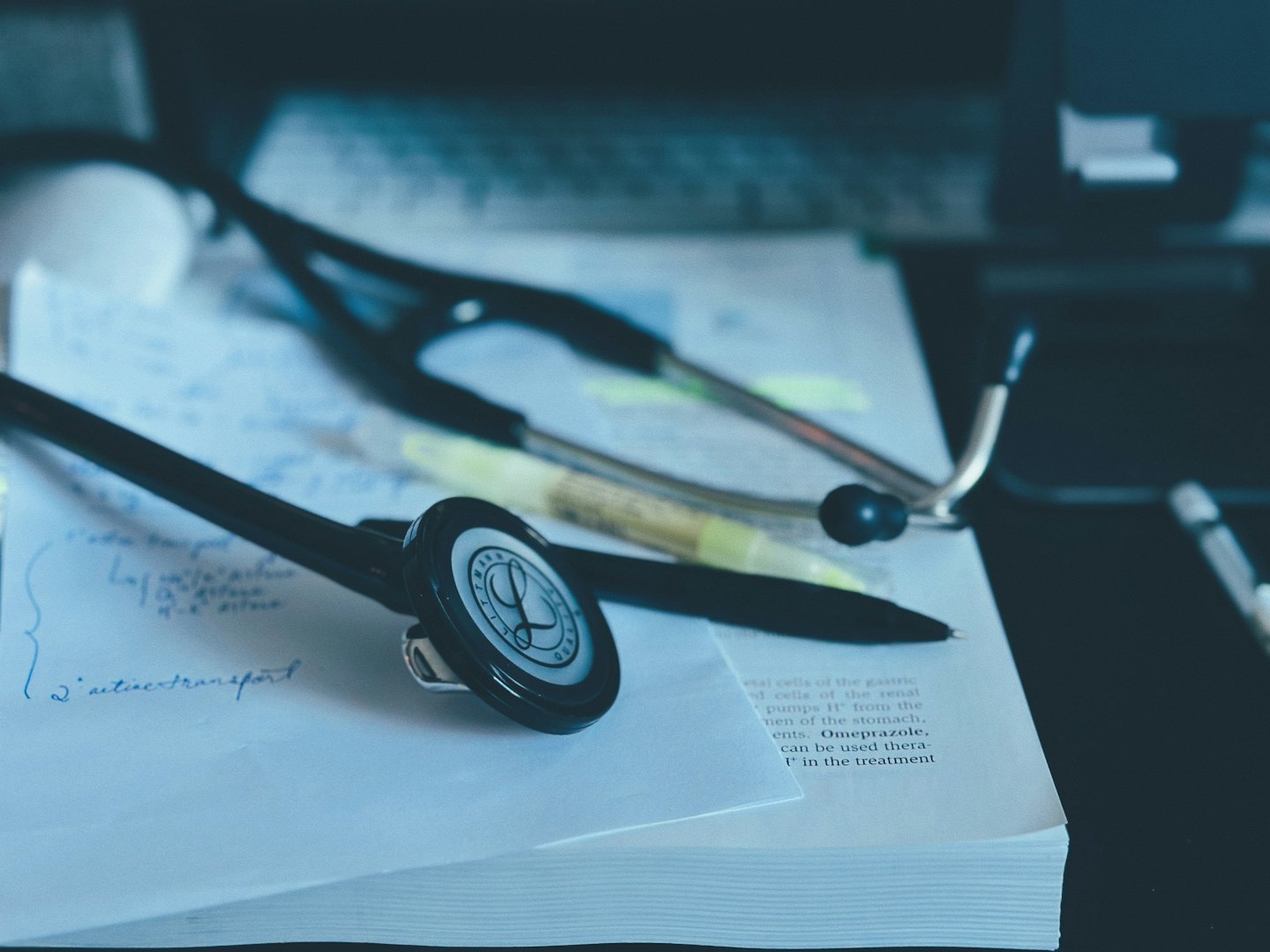 Stetoscopio e penna appoggiati su un libro di testo medico aperto.